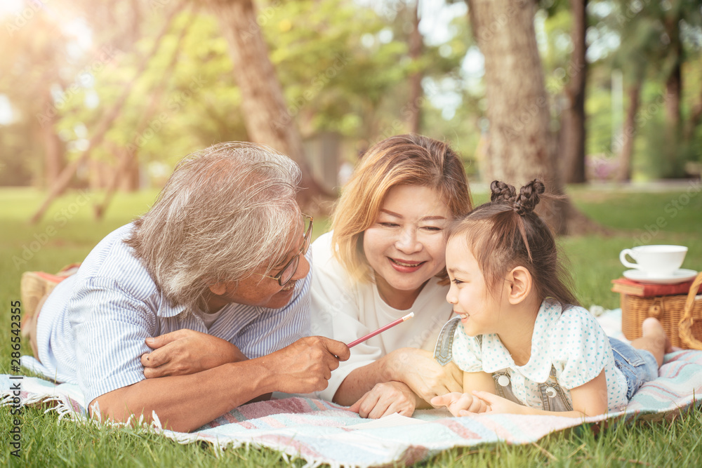 Grandmother,Grandfather and grand daughter enjoying sunny garden holiday together, outdoors space, leisure lifestyle,happy teaching with flare light sky in park. Grandmother,Grandfather and grand daughter enjoying sunny garden holiday together, outdoors space, leisure lifestyle,happy teaching with flare light sky in park.