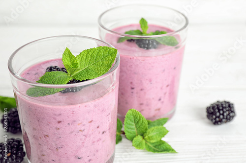 Delicious blackberry smoothie in glasses on white table, closeup