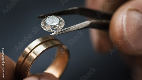Jeweler craftsman selects a gem for a future gold ring, close-up photo