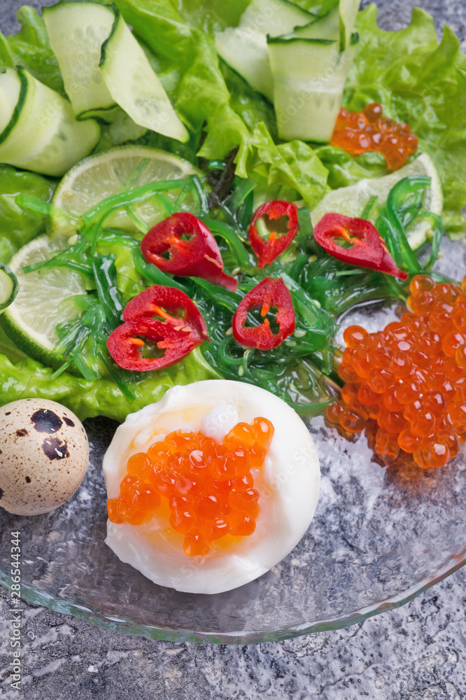 fresh gourmet salad with red salmon caviar and chuka, eggs and vegetables. close up. Protein luxury delicacy healthy food. flat lay fresh gourmet salad with red salmon caviar and chuka, eggs and vegetables. close up. Protein luxury delicacy healthy food. flat lay