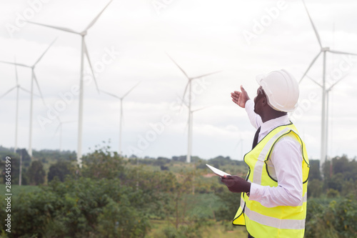 African Engineer standing and hoding laptop with wind turbine © arrowsmith2