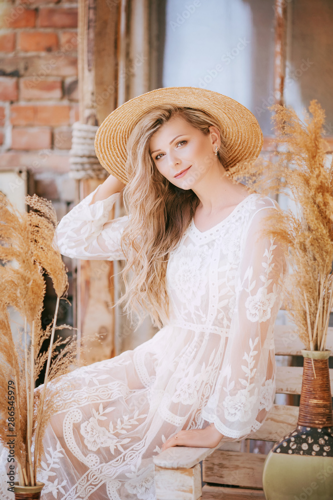 Portrait of beautiful young blonde woman with makeup  in hat and white dress
