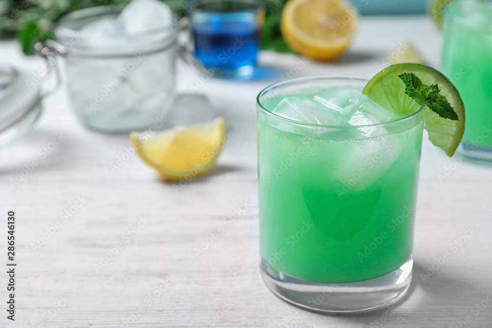 Glass of delicious cocktail with ice on white wooden table. Space for text Glass of delicious cocktail with ice on white wooden table. Space for text