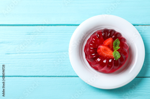 Delicious red jelly with strawberry and mint on light blue wooden table, top view. Space for text photo