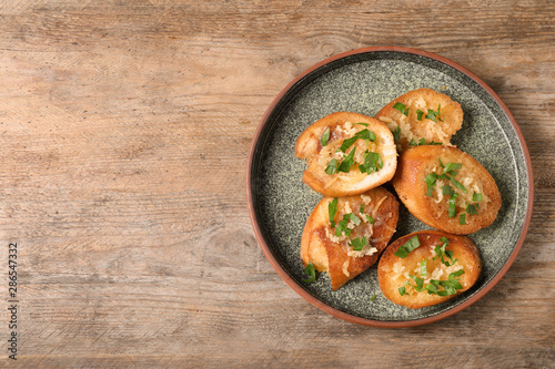 Slices of toasted bread with garlic, cheese and herbs on wooden table, top view. Space for text