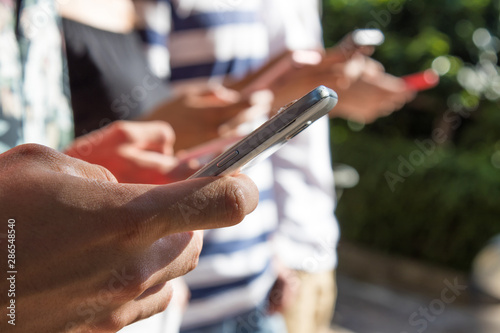 closeup of hands with mobile phone in outdoor group