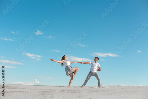 Romantic couple dancing in sand desert at blue sky background