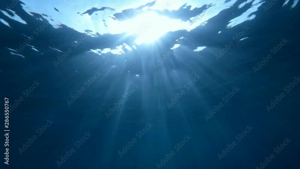Slow motion, Sunlight rays shining through ocean surface,  underwater shot