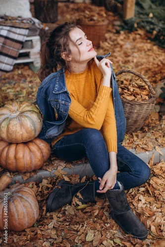 Beautiful girl in autumn garden with yellow pumpkins