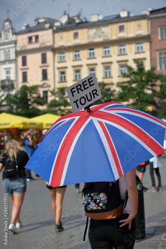 Fototapeta Naklejka Na Ścianę i Meble -  young woman with umbrella in United Kingdom national colors and inscription at to FREE TOUR, city center