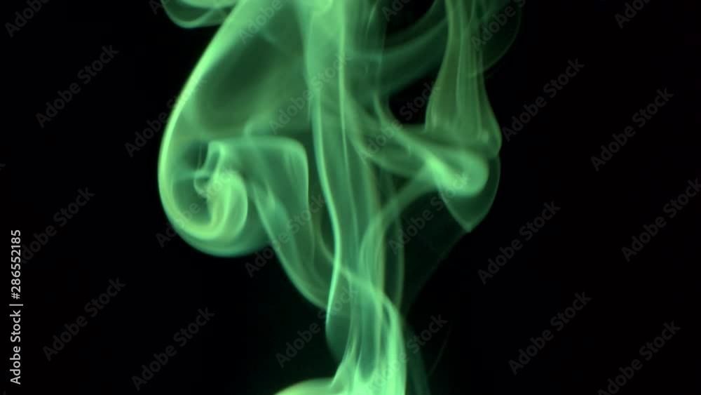 Thin trickle of bright green smoke slowly billow rising swirl up. Colored smoke blowing to top. Closeup, isolated on black background. Thin trickle of bright green smoke slowly billow rising swirl up. Colored smoke blowing to top. Closeup, isolated on black background.