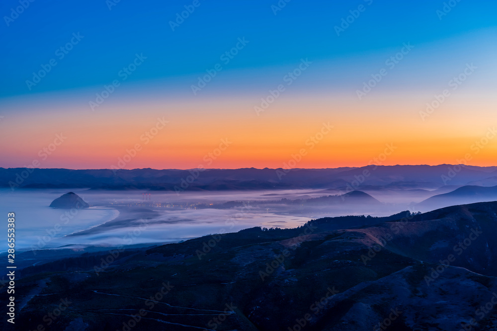 Sunset over Ocean and City and Mountains