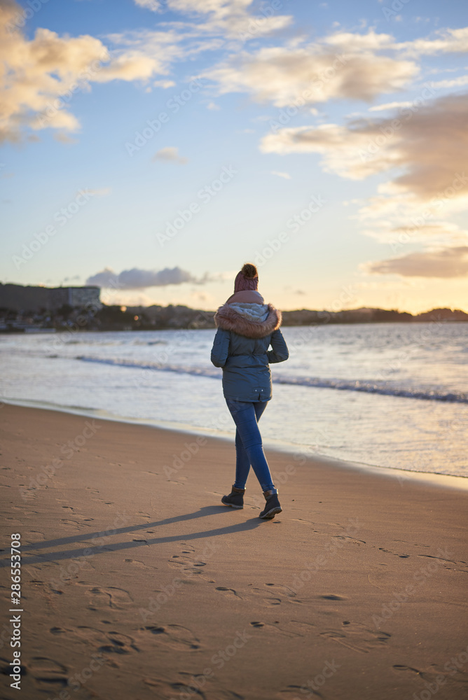 Young woman going for a walk on the beach in winter