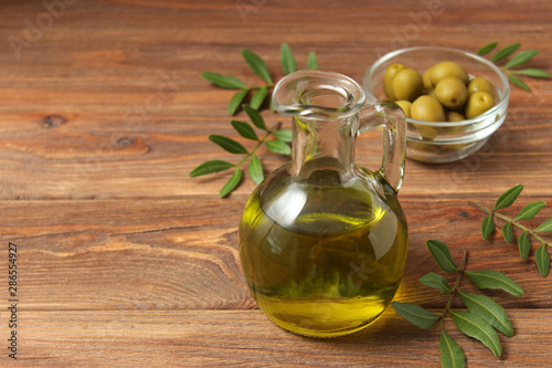 olive oil, green leaves and olives on the table.