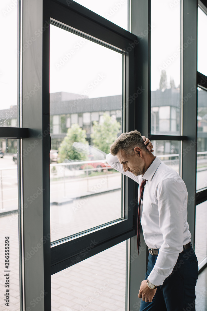 upset businessman in suit standing near windows in office upset businessman in suit standing near windows in office