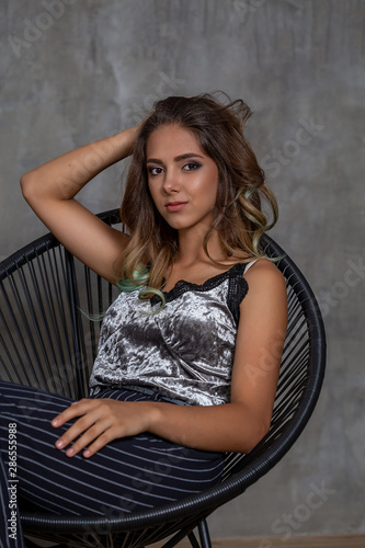 Closeup woman portrait. Young contented fashionable girl posing in sitting in a chair. Fashion.