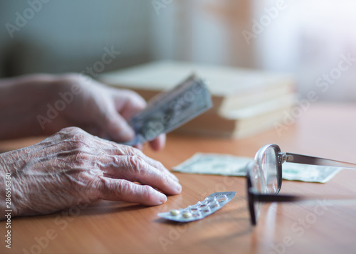 Money in the hands of an old woman. An elderly woman pensioner counts money. Elderly financial concept. Banknotes in the hands of an old woman.