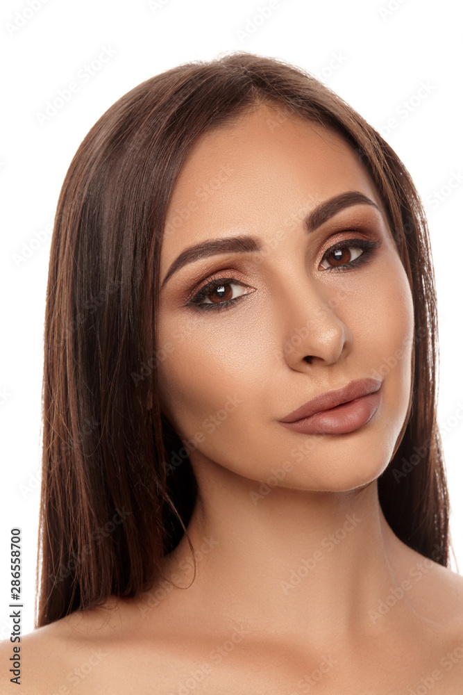 Fototapeta premium Close up portrait of a brunette nude model girl with professional evening make-up and plump lips, posing isolated on white background.