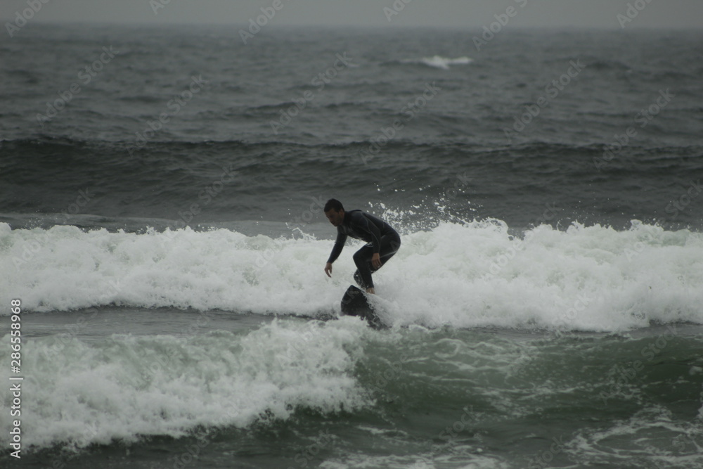 surfing the waves on the beach of Matosinhos in Porto, Portugal. August 2019