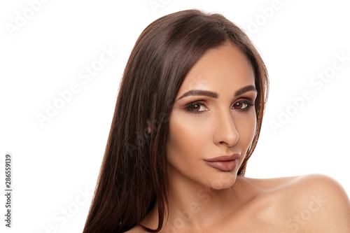 Close up portrait of a brunette nude model girl with professional evening make-up and plump lips, posing isolated on white background.
