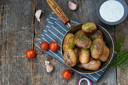 Fried potatoes with herbs and sour cream in a rustic style on a wooden table