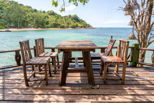 Wooden table and chairs in empty beach cafe next to sea water. Island Koh Phangan  Thailand