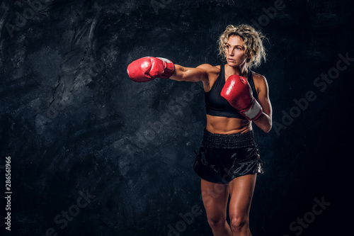 Blonde experienced boxer is demonstrating her tactic attack wearing special gloves.