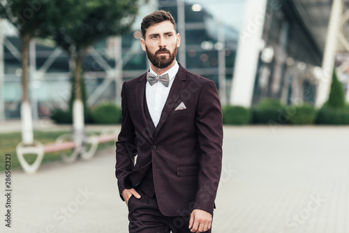 Young and successful. Handsome young man in full suit adjusting his jacket while standing outdoors