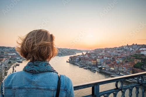 redhead woman observing the sunset in porto, portugal on the bridge over the river