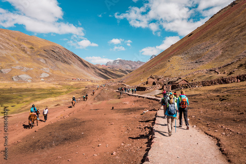 Tourists walking to Vinicunca Rainbow Mountain through stunning barren mountain landscape  Peru