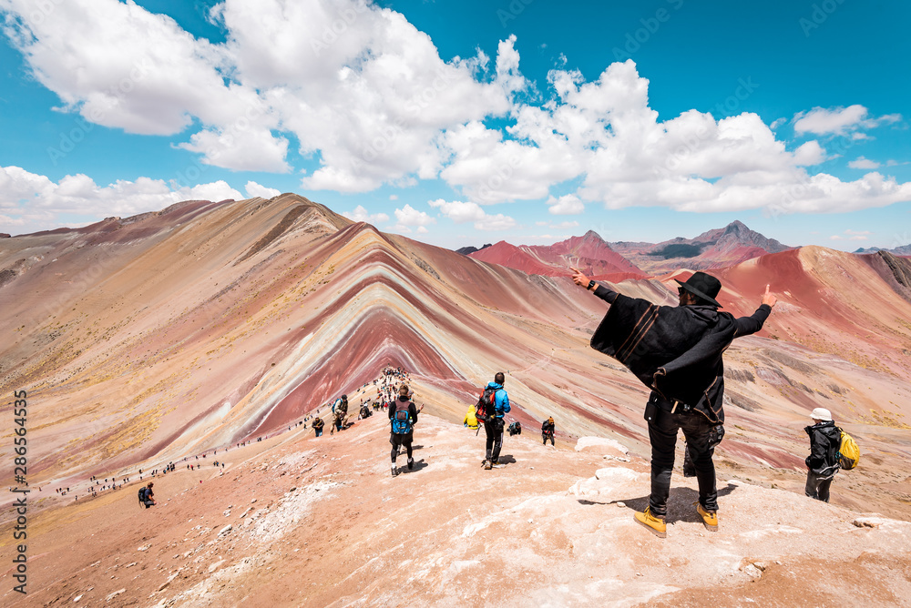Vinicunca Rainbow Mountain, tourists standing on top of the mountain and admiring the view, Cusco, Peru
