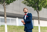 Portrait of sexy handsome fashion businessman model dressed in elegant blue suit posing on street background.