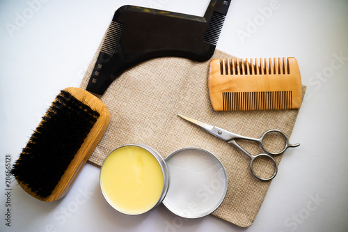 Expert beard care supplies such as comb, brush, scissor and wax made of natural ingredients. Flat lay on a white background