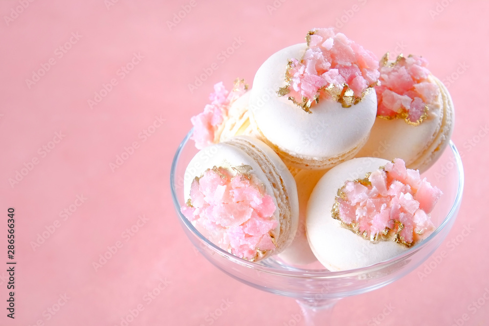 Minimalistic composition with bunch of white french macaron sweets with pink crystal shaped marmalade decoration over grunged concrete texture background. Top view, close up, flat lay, copy space. Minimalistic composition with bunch of white french macaron sweets with pink crystal shaped marmalade decoration over grunged concrete texture background. Top view, close up, flat lay, copy space.