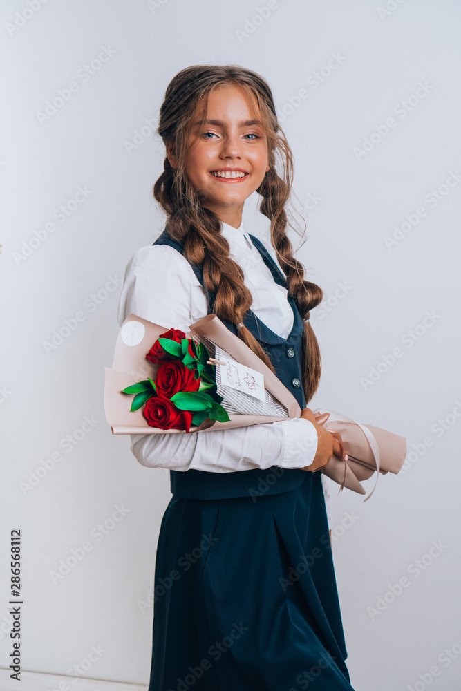 Schoolgirl posing with a bouquet of flowers. Girl in a school suit. Day of Knowledge. September 1. Schoolgirl posing with a bouquet of flowers. Girl in a school suit. Day of Knowledge. September 1.