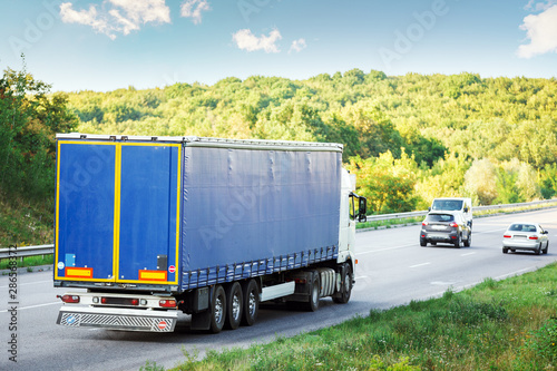 Arriving white truck on the road in a rural landscape at sunset