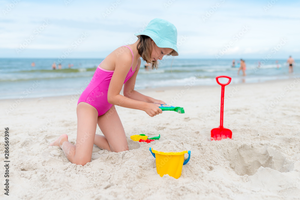 Happy child playing with sand at the beach in summer Happy child playing with sand at the beach in summer