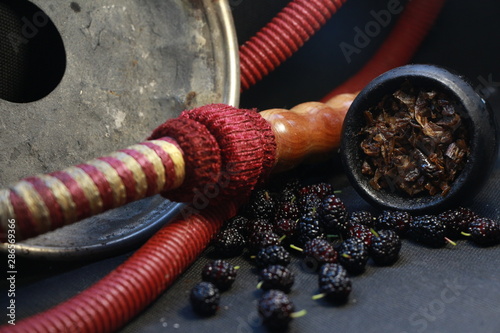 bowl with tobacco for hookah. fruits and berries on a black background. smoke hookah