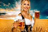 Young sexy oktoberfest girl waitress, wearing a traditional Bavarian or german dirndl, serving big beer mugs with drink isolated on yellow background.