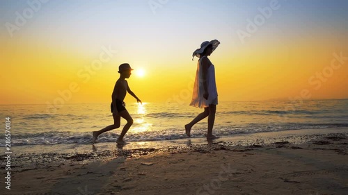 Wallpaper Mural Tourism and travel vacation. Adorable family having fun on beach against sunset. Mother and son walk on beach an play, cinematic steadicam shot Torontodigital.ca