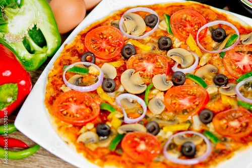 Popular colorful ingredients as like tomatoes, cheese, mushroom, capsicum, olives and other ingredients baked healthy Pizza.