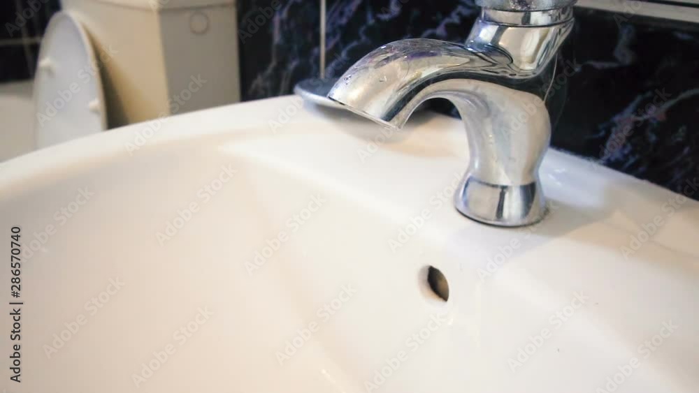 Female hand stopping tap water in bathroom, SLOW MOTION Female hand stopping tap water in bathroom, SLOW MOTION