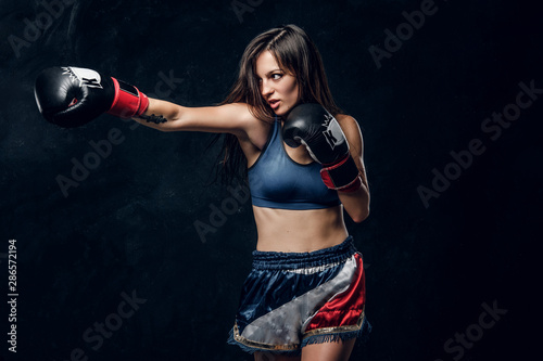 Beautiful female boxer is demonstrating her tactic attack while posing for photographer.