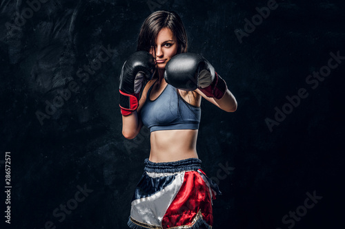 Fototapeta Naklejka Na Ścianę i Meble -  Young attractive female boxer with long hair and boxing gloves is ready to fight.