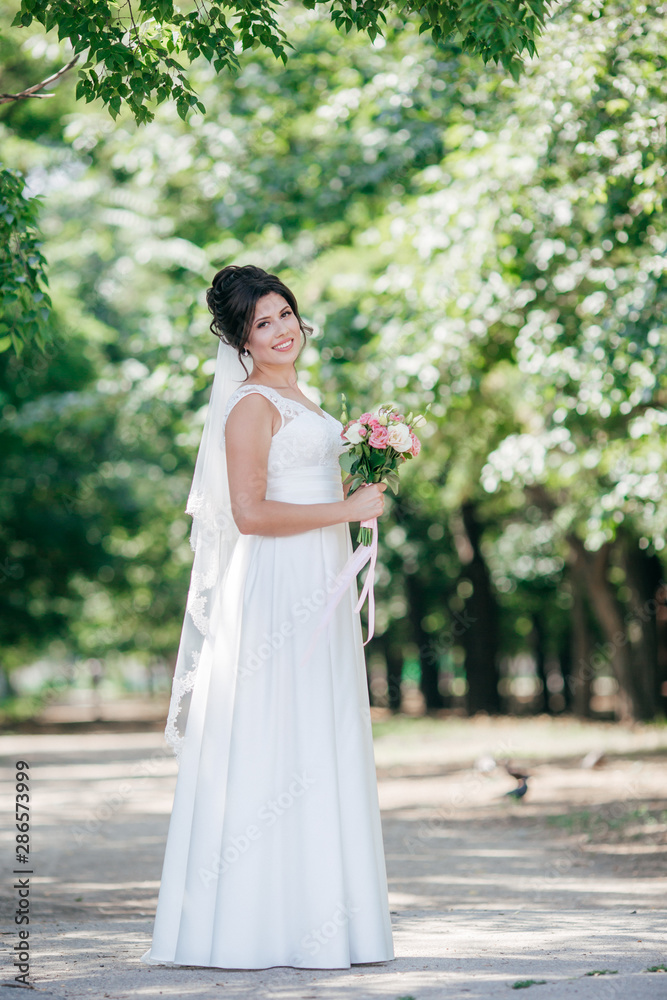 Beautiful bride with stylish make-up in white dress in spring garden 