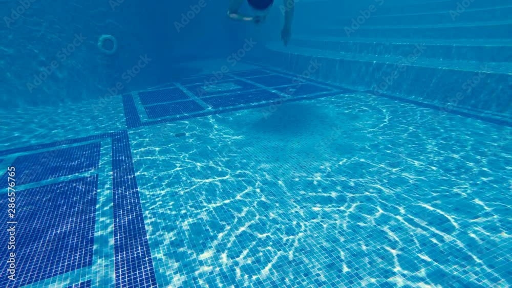 Attractive teen swimming underwater in luxury pool with closed nose by hand, slow motion Attractive teen swimming underwater in luxury pool with closed nose by hand, slow motion