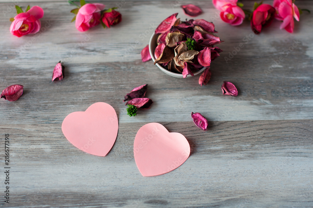 Dry air petals pink roses lie on the table in a white Cup, near with them lie pink paper hearts Dry air petals pink roses lie on the table in a white Cup, near with them lie pink paper hearts