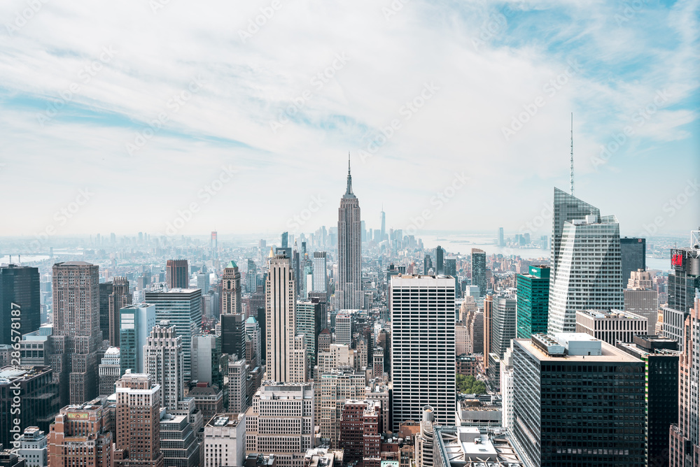 New York City Manhattan, NYC/ USA - 08 21 2017: Top of the Rock panorama view over skyline from Rockefeller center to NYC and the Empire State building on a light cloudy sunny day with blue sky