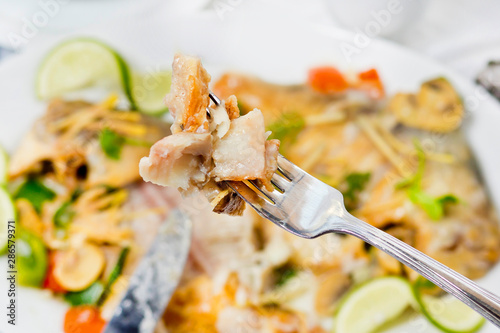 Pieces of Pomfret fish on a fork close-up. photo