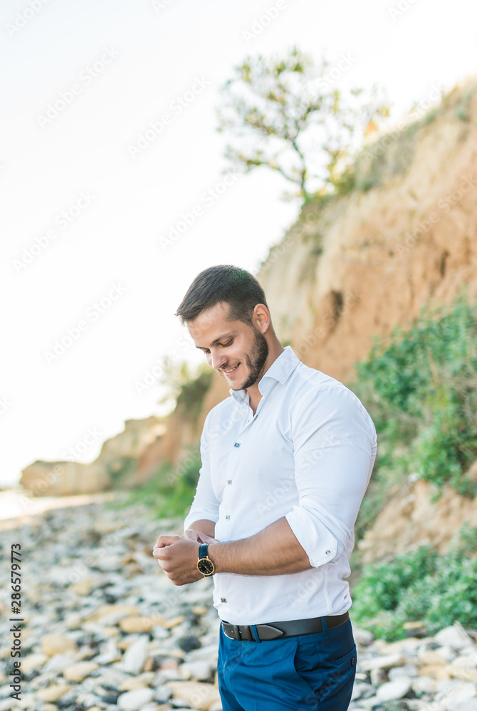 Handsome male groom waiting for the bride on the background of beautiful architecture. Rich groom on the wedding day. Elegant groom in a black suit . Wedding day
